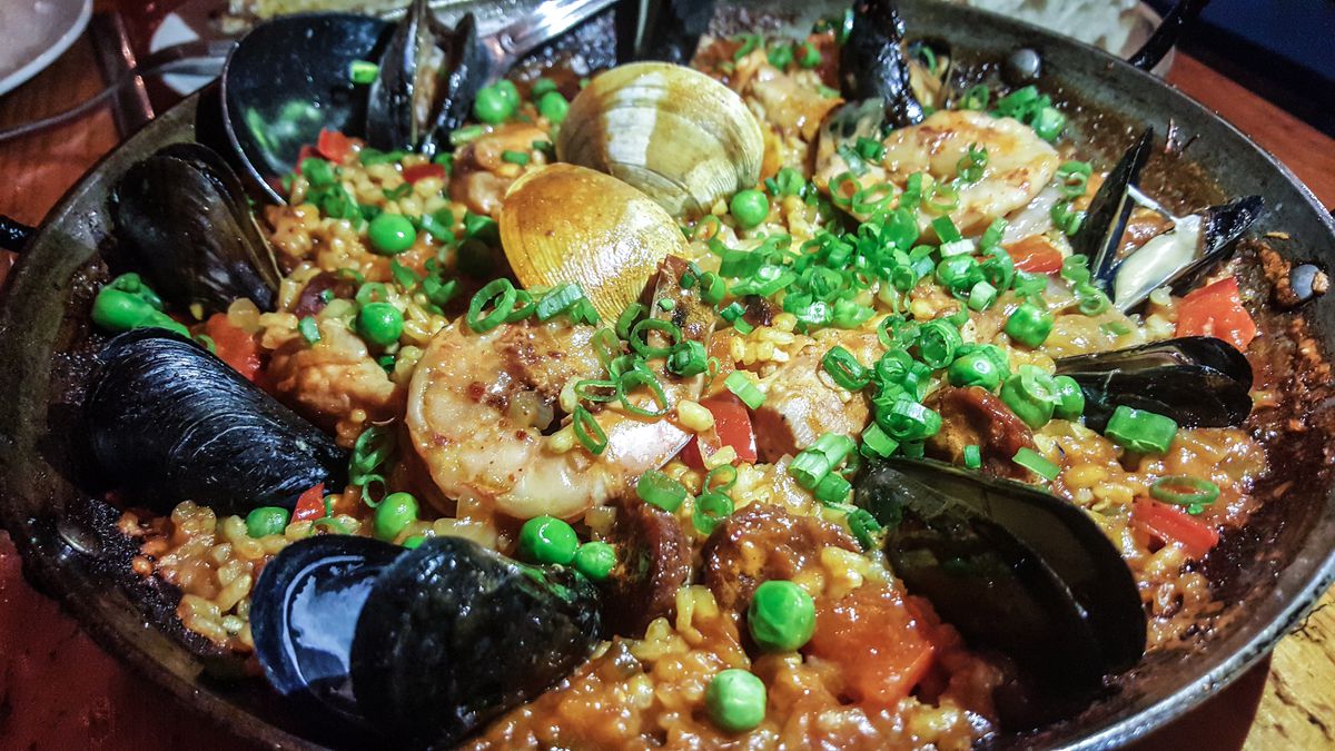 Mussels, shrimp, and clams sit atop a skillet of rice and vegetables