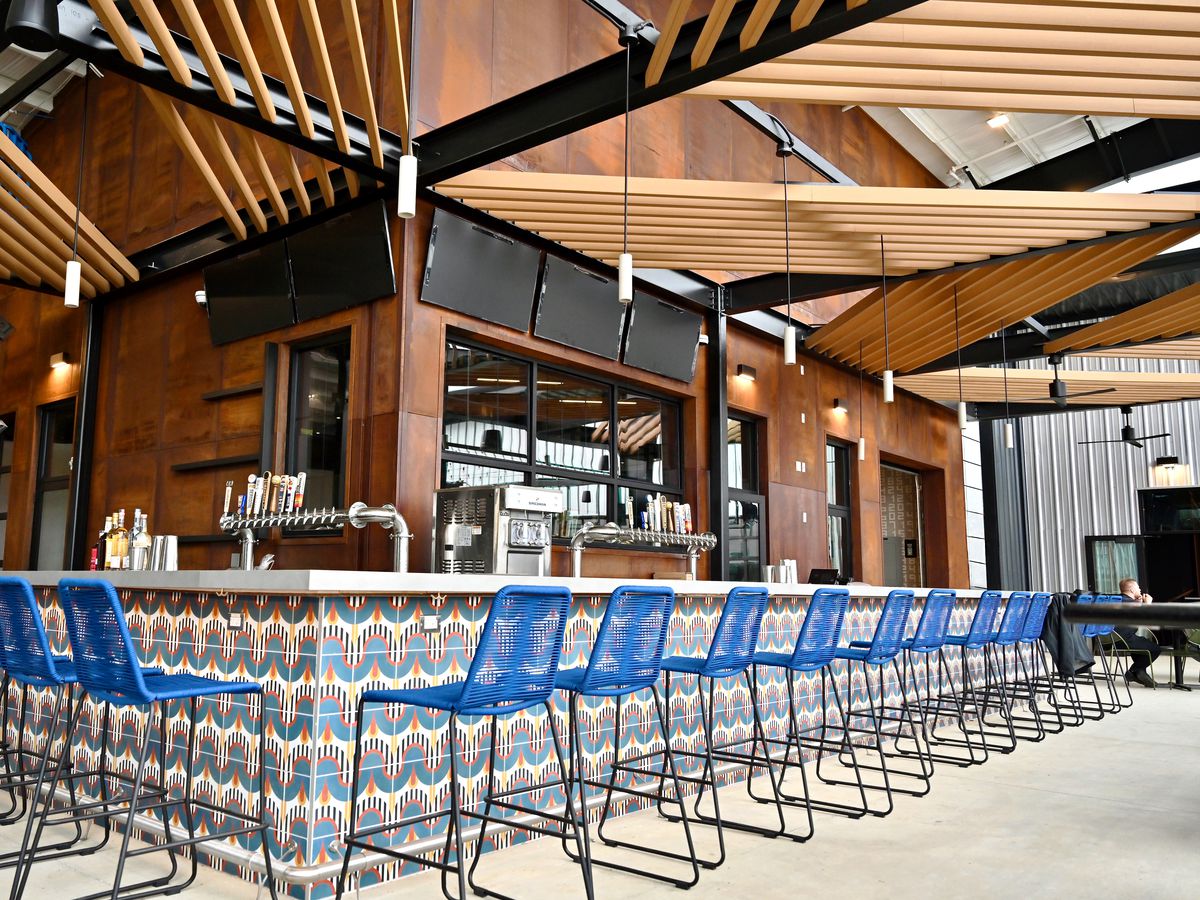 A bar lined with bar seats and TVs at Home Run Dugout.