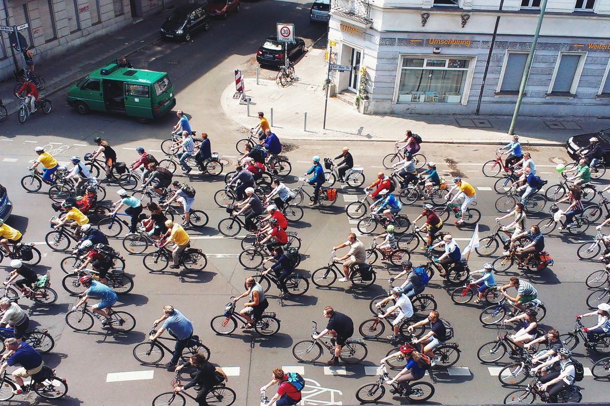 A stream of bikers rides down a city street.