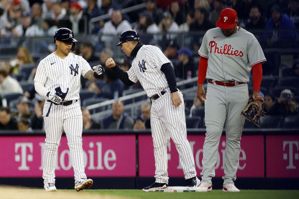 Gleyber Torres celebrates with first base coach Travis Chapman of the New York Yankees after hitting an RBI single during the first inning against the Philadelphia Phillies at Yankee Stadium on April 03, 2023 in the Bronx borough of New York City.