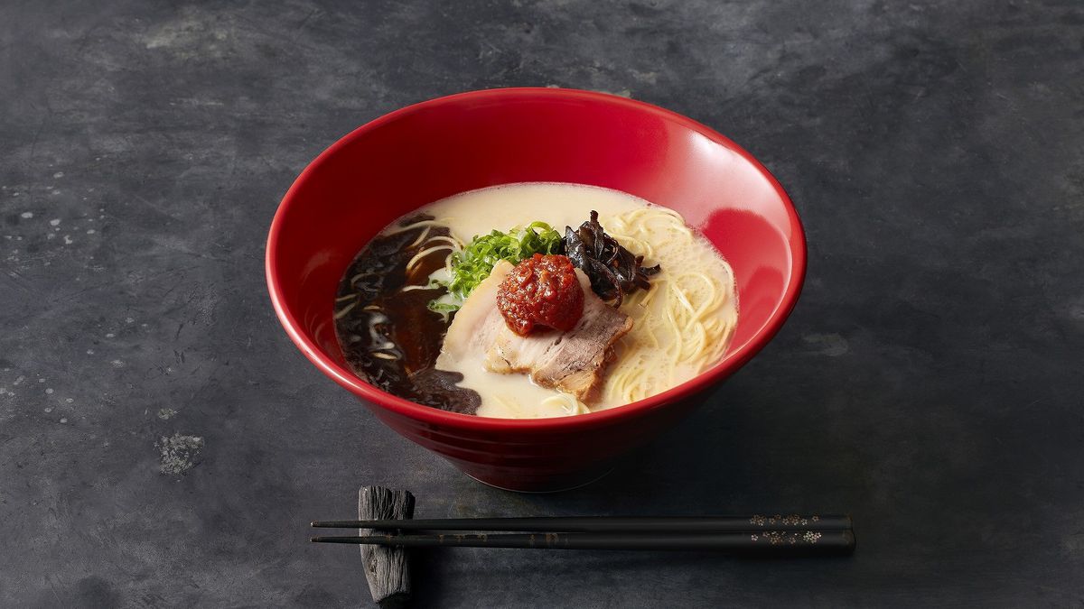 Ippudo Ramen in a red bowl, with wooden chopsticks in front.
