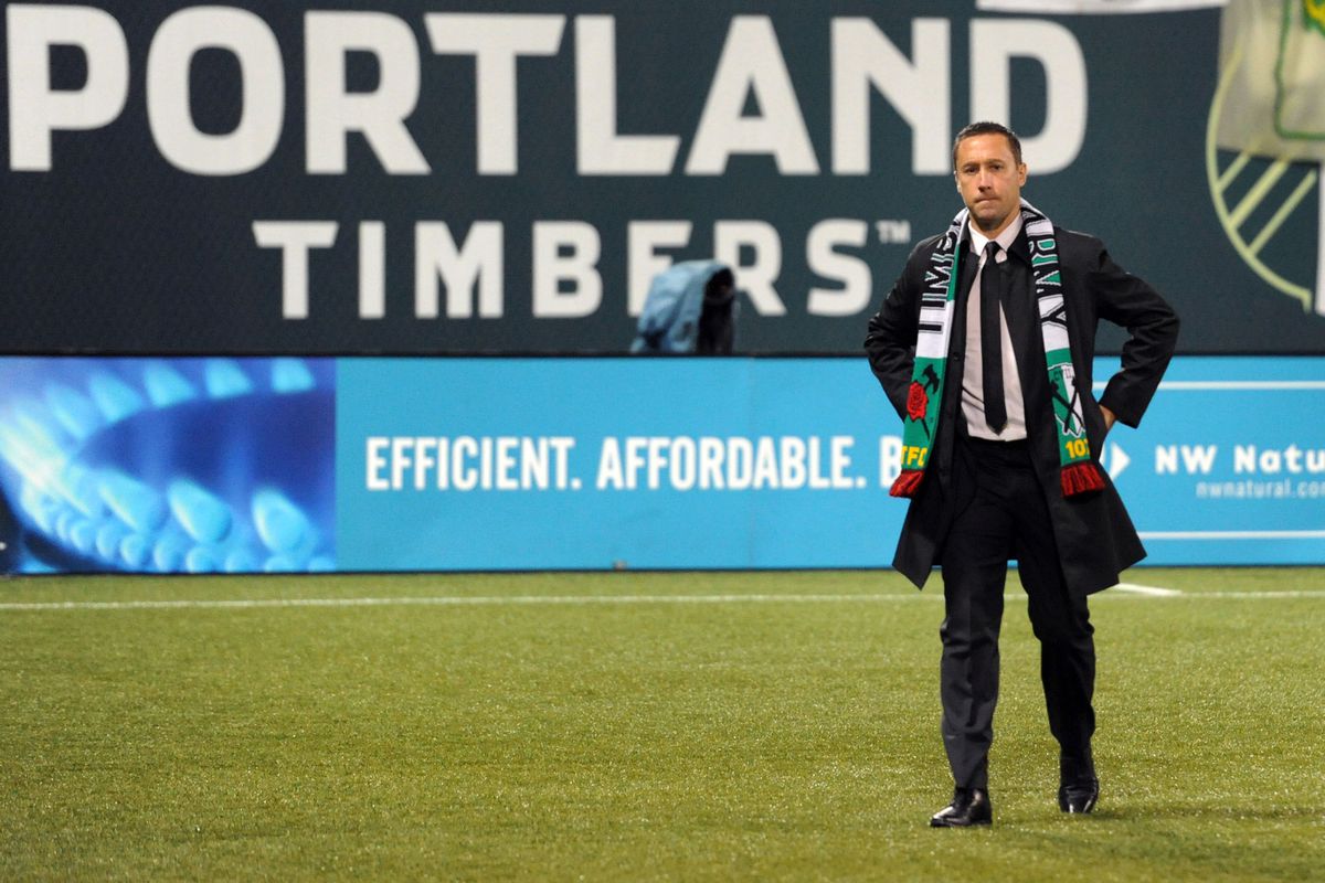 Caleb Porter poses in front of the Timbers' graphic at Providence Park.