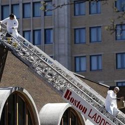 FBI investigators walk down a fire truck ladder with  bags from a building at the corner of Boylston Street and Fairfield Street , Wednesday, April 17, 2013, in Boston. Investigators in white jumpsuits fanned out across the streets, rooftops and awnings around the blast site in search of clues on Wednesday.