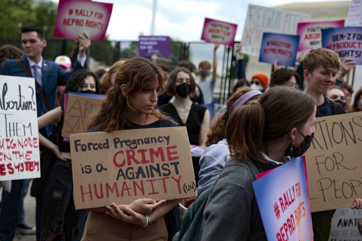 Protesters hold signs reading, “Forced pregnancy is a crime against humanity,” among others.