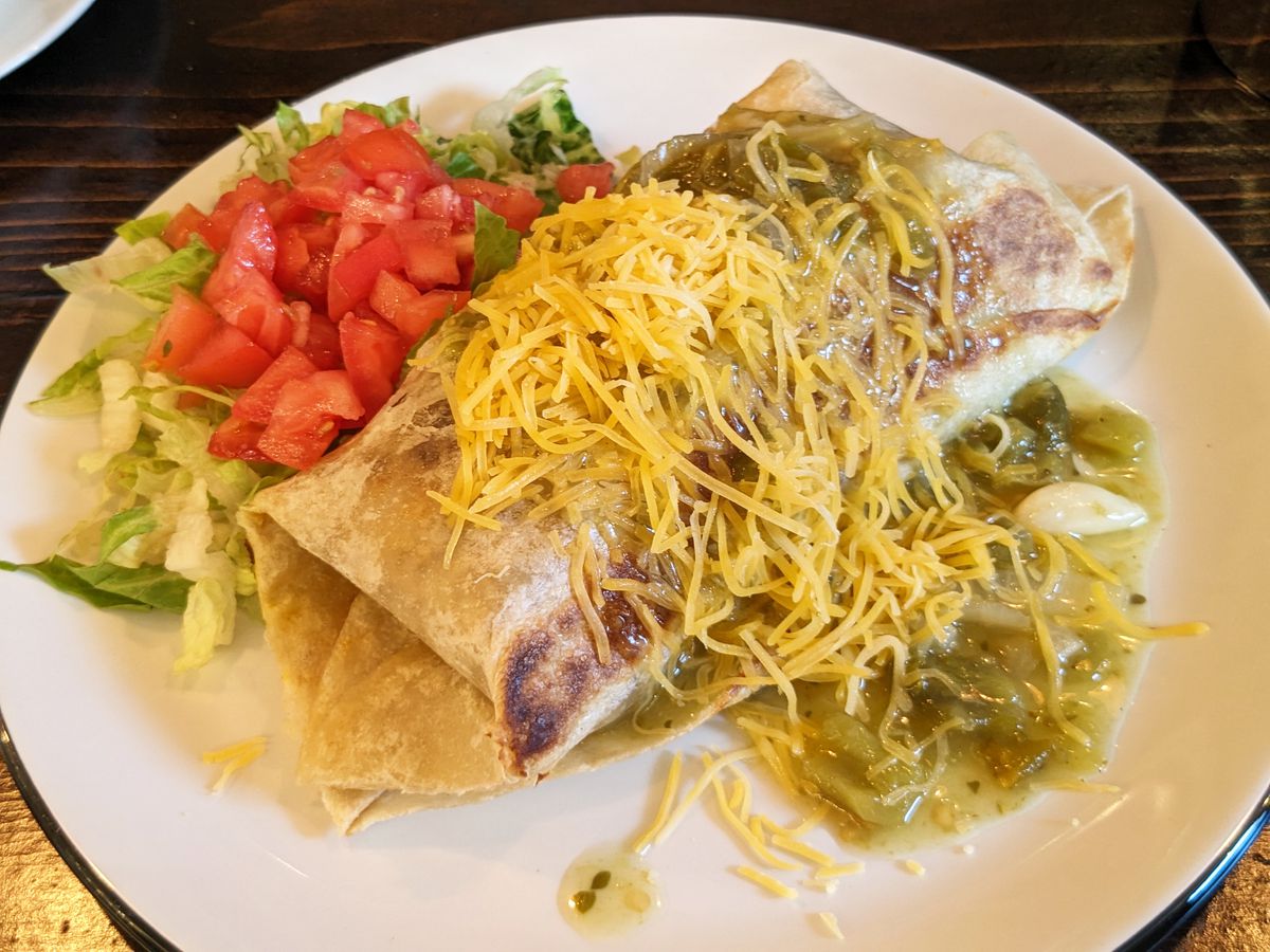 A burrito covered with yellow cheese.