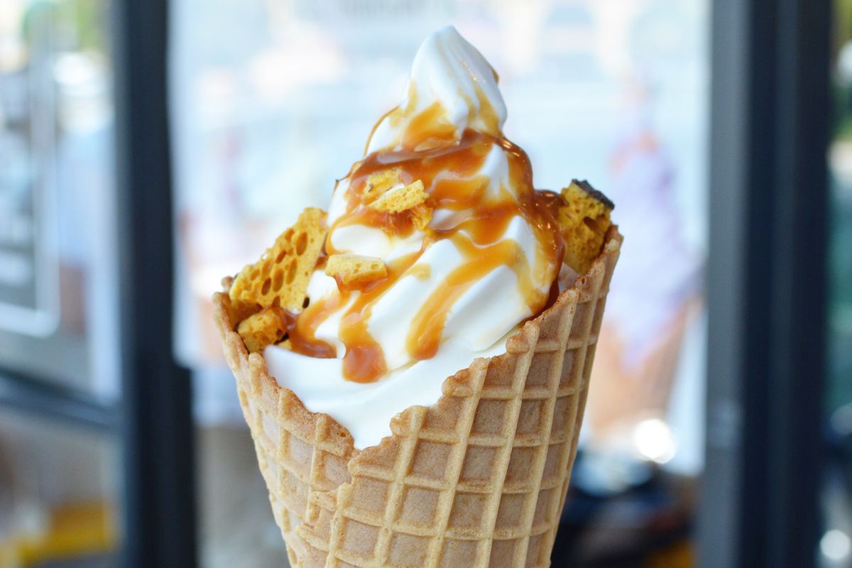 A soft serve ice cream inside a cone with a drizzle of caramel