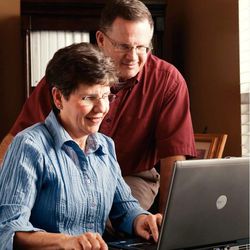 A couple reads the scriptures while working on a computer.