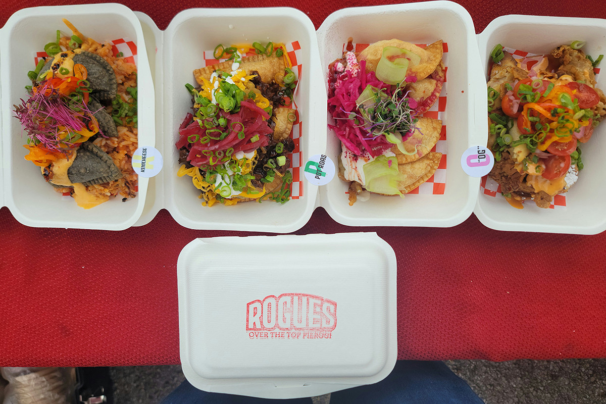 Four food containers with pierogies and toppings.
