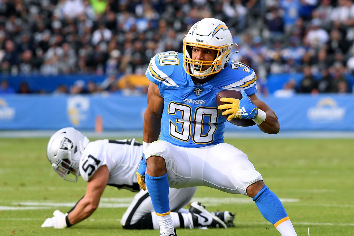 Austin Ekeler #30 of the Los Angeles Chargers cuts back after breaking a tackle from Will Compton #51 of the Oakland Raiders during the second quarter at Dignity Health Sports Park on December 22, 2019 in Carson, California.