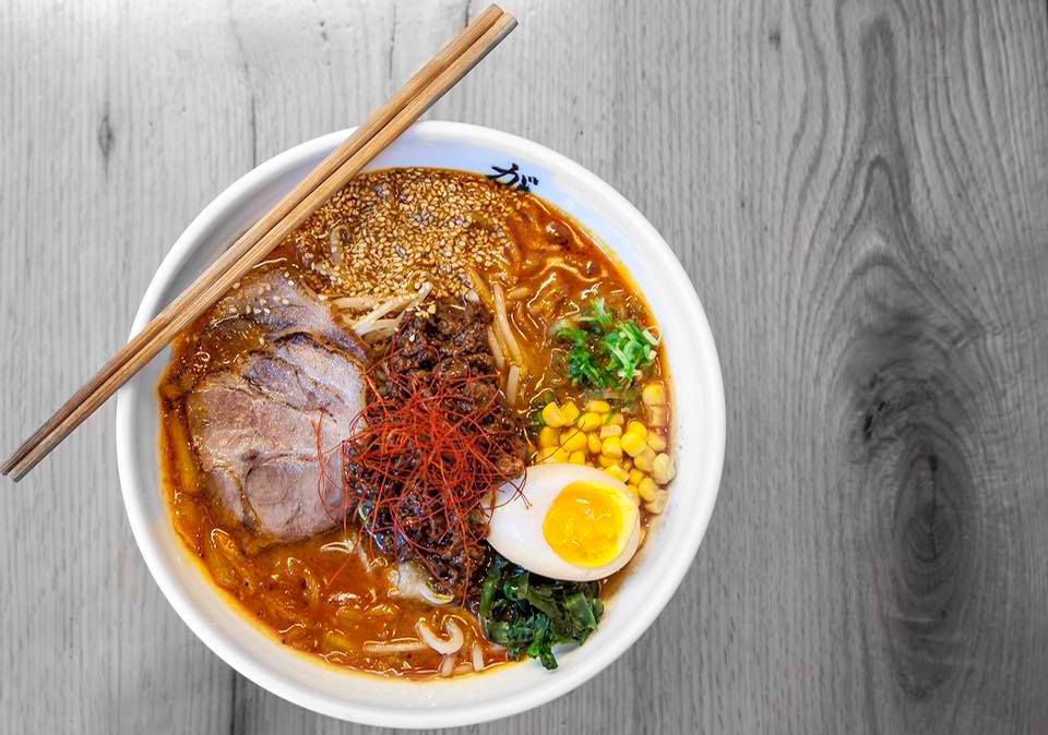 A bowl of ramen filled with spicy broth, noodles, an egg, and chashu.