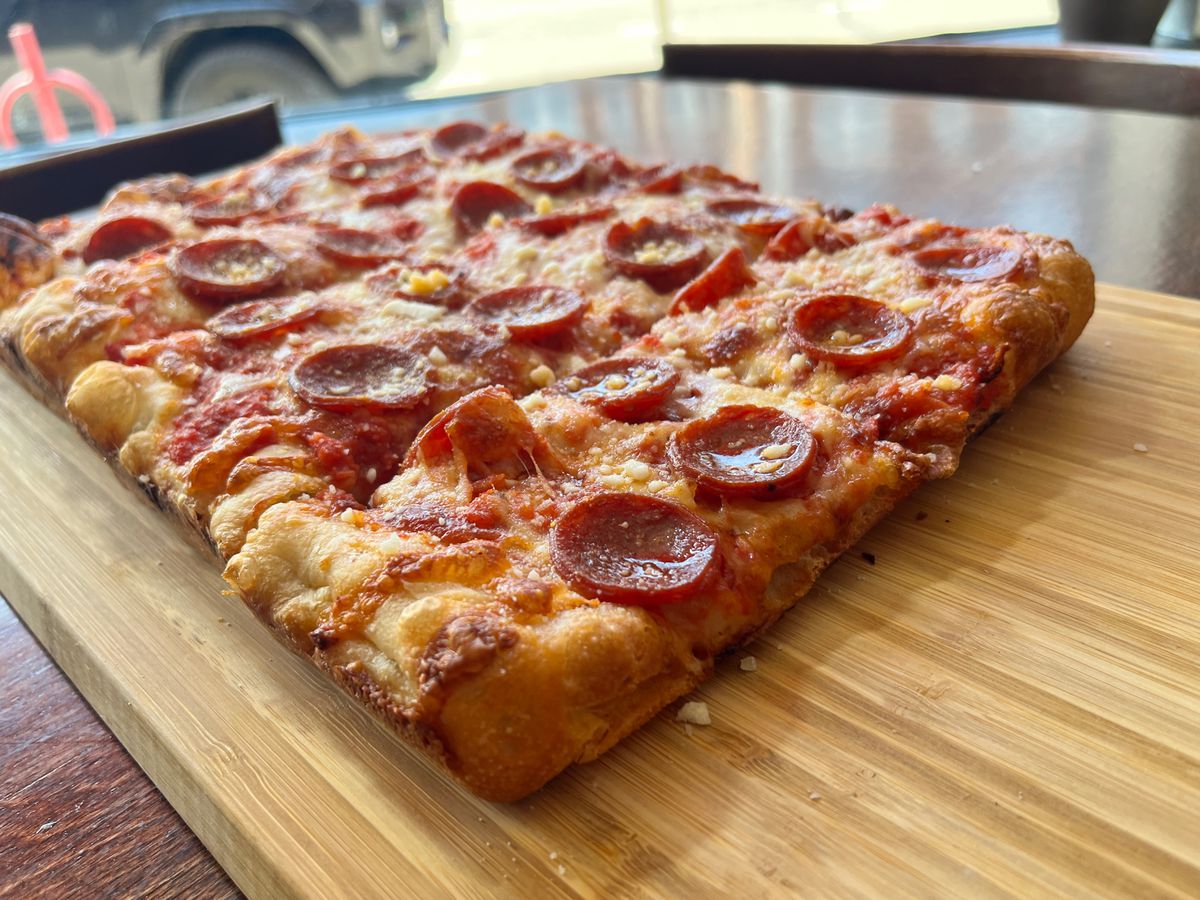 A rectangular pepperoni pizza on a butcher’s block. 