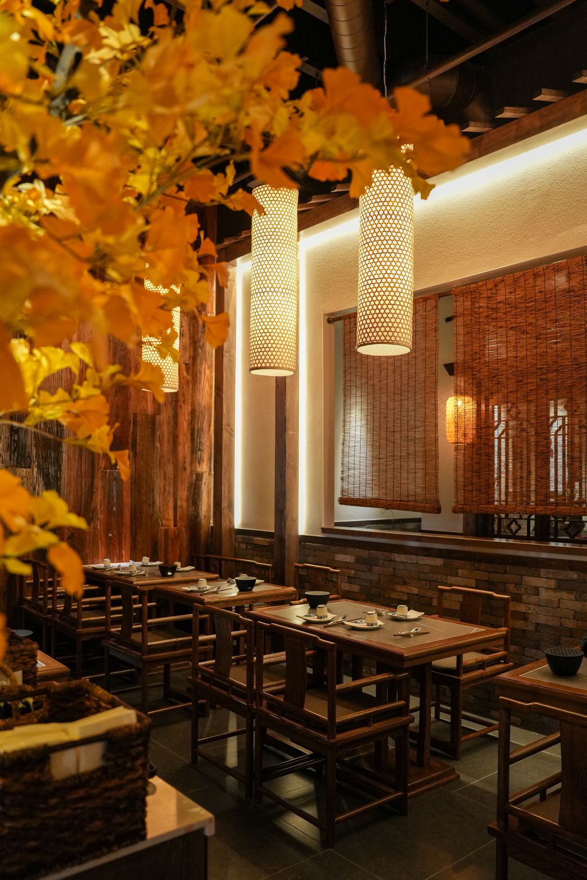 The interior of a Chinese restaurant with lanterns, wooden accents, and trees.