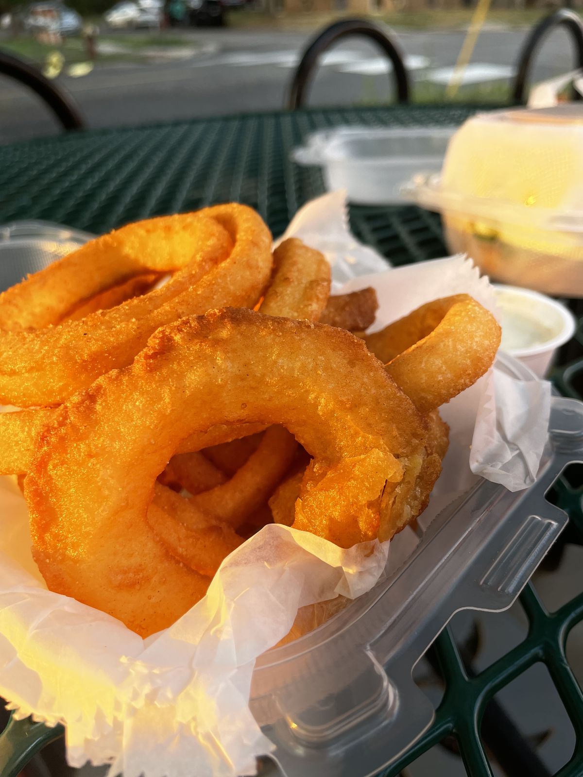 A plastic dish of onion rings on a table outside. 