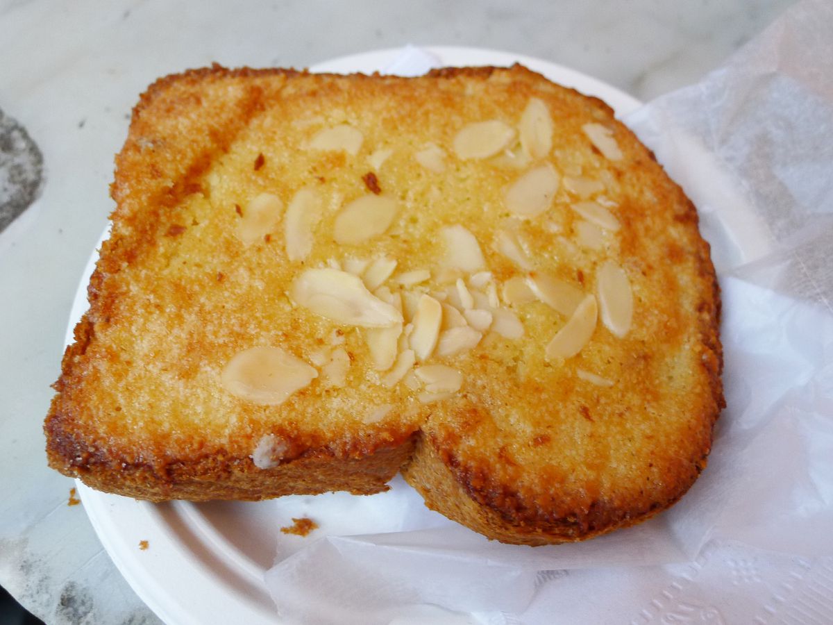 A piece of brown glistening toast embedded with slivered almonds.