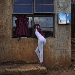 In this photo taken Friday, Dec. 9, 2016, a young ballerina looks through the window at others practicing under the instruction of Kenyan ballet dancer Joel Kioko, 16, in a room at a school in the Kibera slum of Nairobi, Kenya. In a country not usually associated with classical ballet, Kenya's most promising young ballet dancer Joel Kioko has come home for Christmas from his training in the United States, to dance a solo in The Nutcracker and teach holiday classes to aspiring dancers in Kibera, the Kenyan capital's largest slum. 