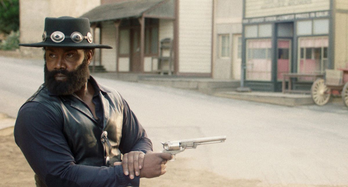 Michael Jai White looks the other way while firing his pistol on an empty Western street in Outlaw Johnny Black.
