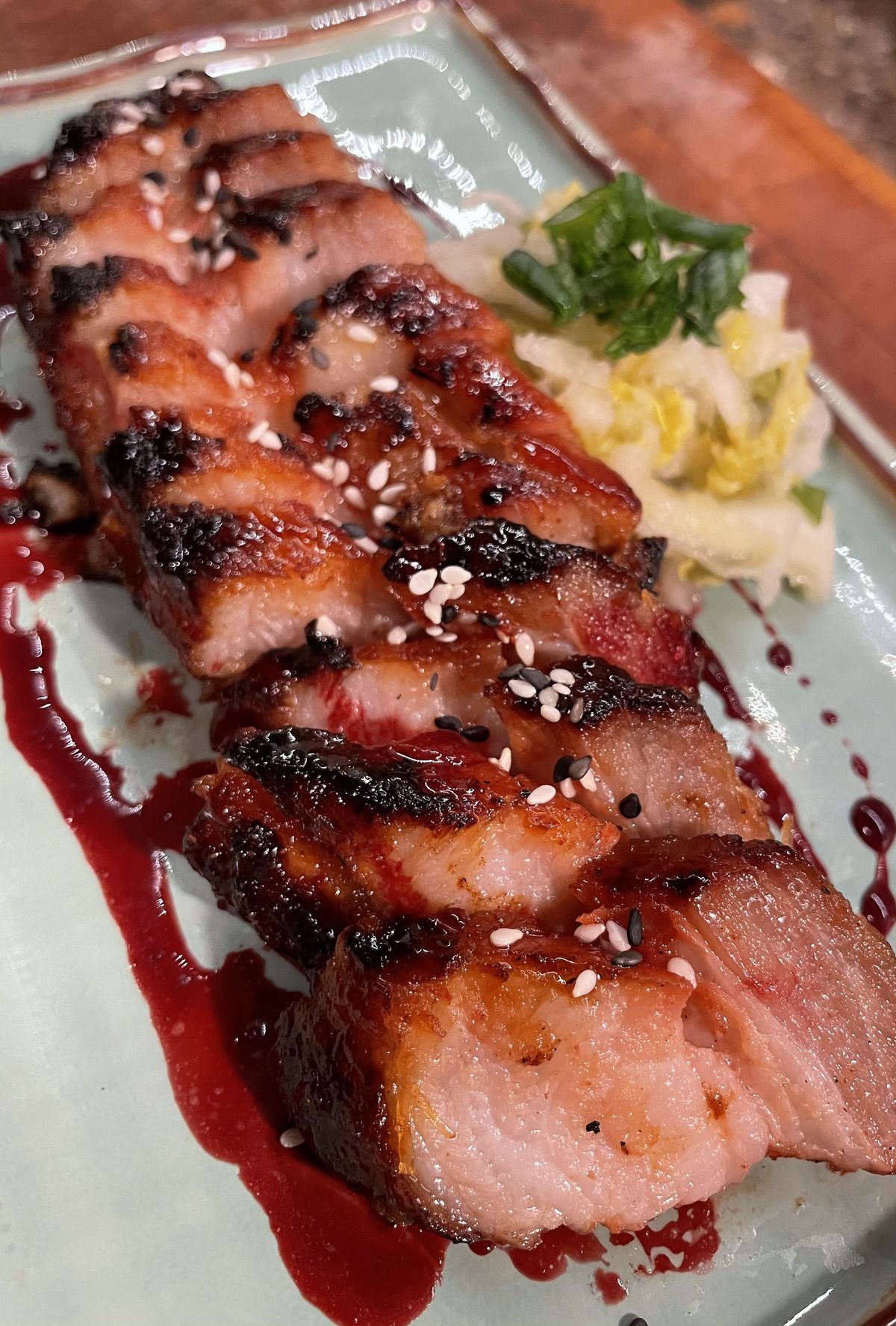 Char siu pork belly with white kimchi layered on a platter, close up. 