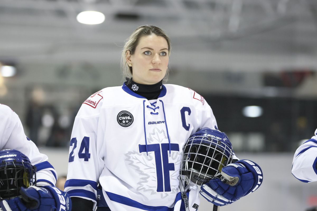 Natalie Spooner stands on the ice for the anthem, holding her helmet.