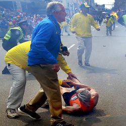 People react to a second explosion at the 2013 Boston Marathon in Boston, Monday, April 15, 2013. Two explosions shattered the euphoria of the Boston Marathon finish line on Monday, sending authorities out on the course to carry off the injured while the stragglers were rerouted away from the smoking site of the blasts. 