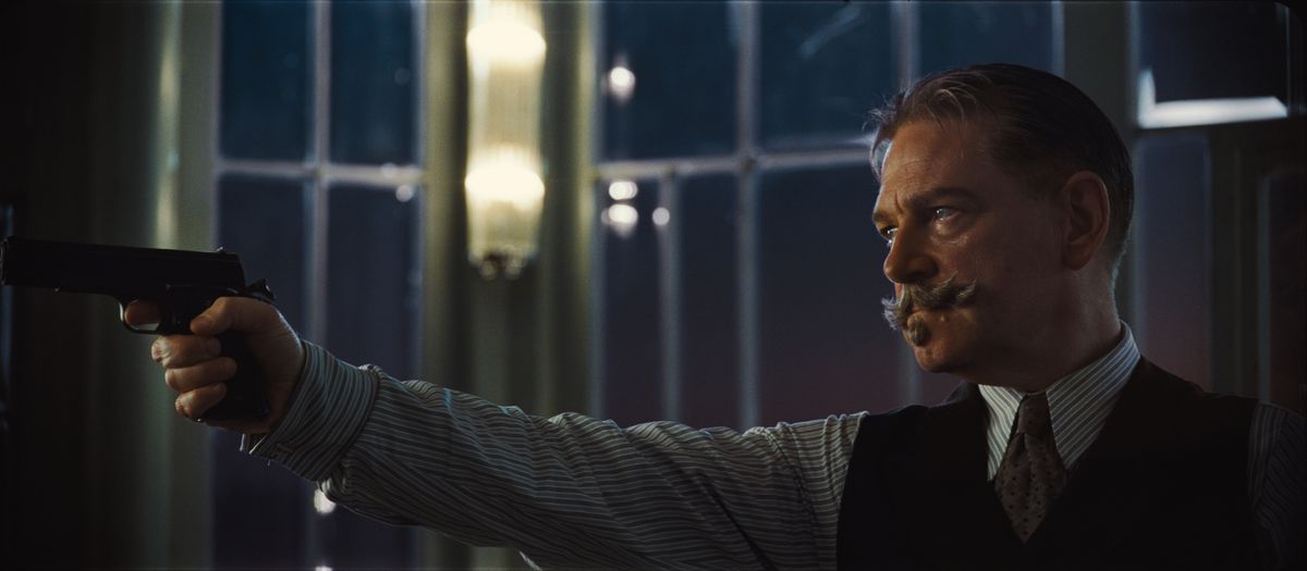 kenneth branagh in death on the nile holds a gun and retains his mustache