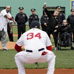 Boston Marathon bombing victim Steven Byrne, midground left, and marathon runners Dick and Rick Hoyt, midground right, throw out ceremonial first pitches as Boston Red Sox's David Ortiz  (34) catches before a baseball game against the Kansas City Royals in Boston, Saturday, April 20, 2013. 