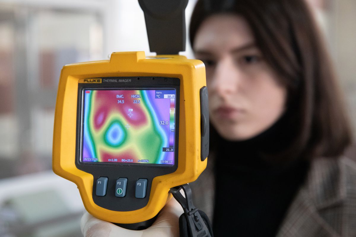 A thermal imaging camera takes a woman’s temperature.
