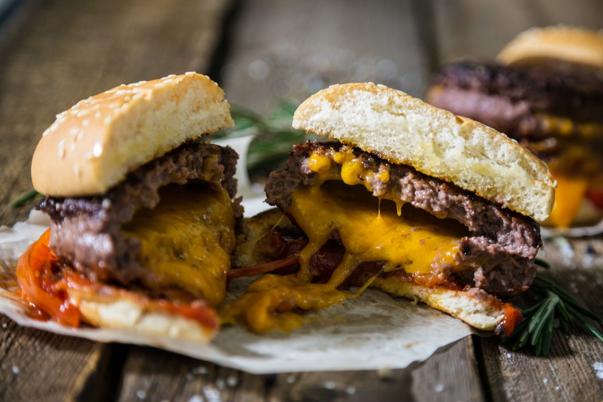 A jucy lucy burger cut in half with cheddar cheese baked into the meat