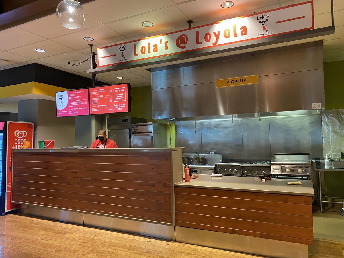 A food hall stall with video screen menus and a vent hood.