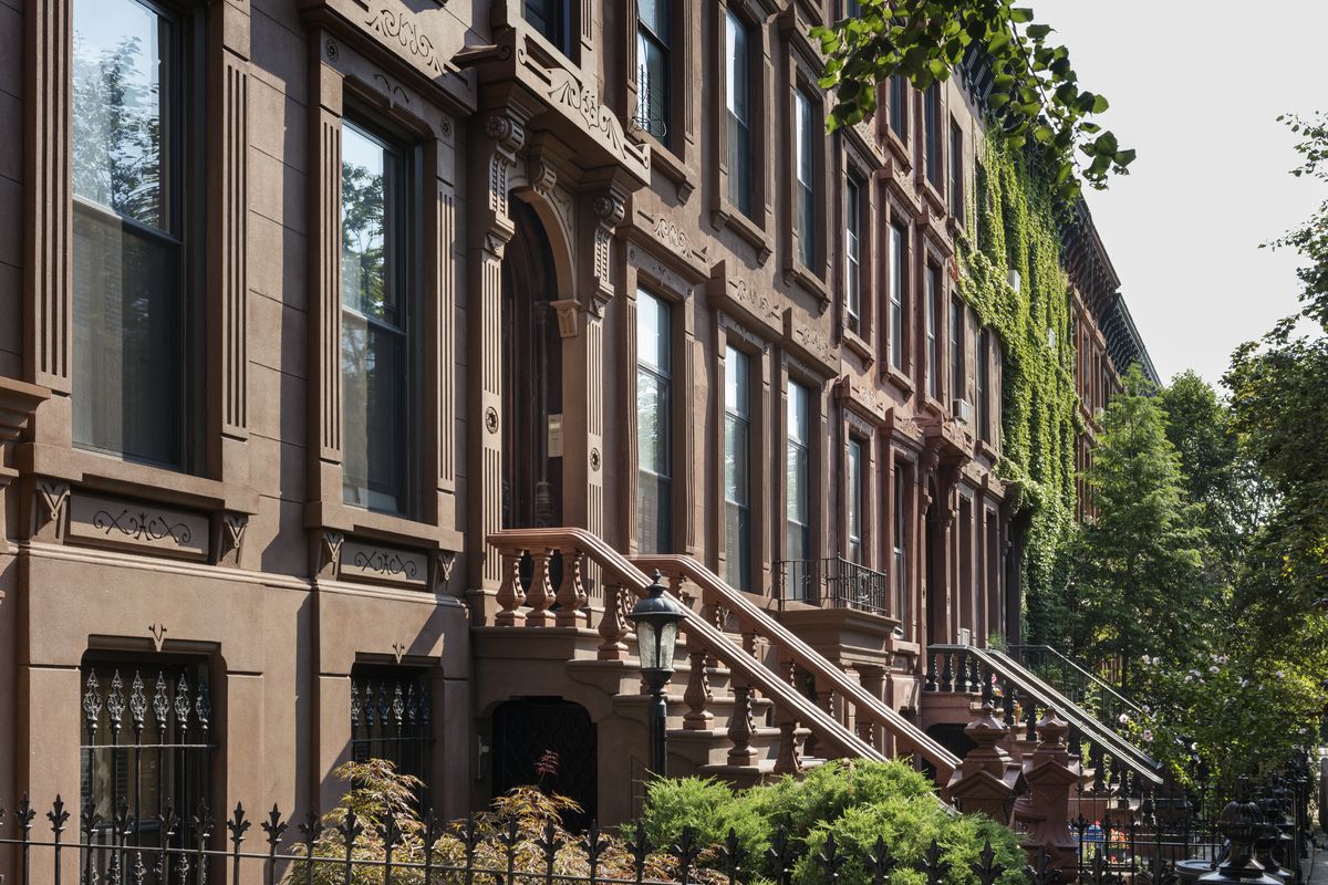 A row of brownstone townhouses on a sleepy, tree-lined block in Brooklyn.