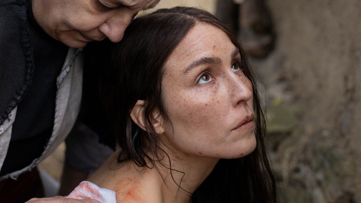 Noomi Rapace in closeup, blood on her shoulder and someone barely visible leaning over her, in&nbsp;You Won’t Be Alone