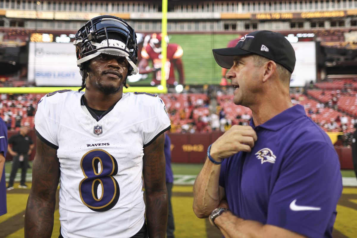 Lamar Jackson #8 of the Baltimore Ravens chats with head coach John Harbaugh of the Baltimore Ravens during an NFL preseason game at FedExField on August 21, 2023 in Landover, Maryland.