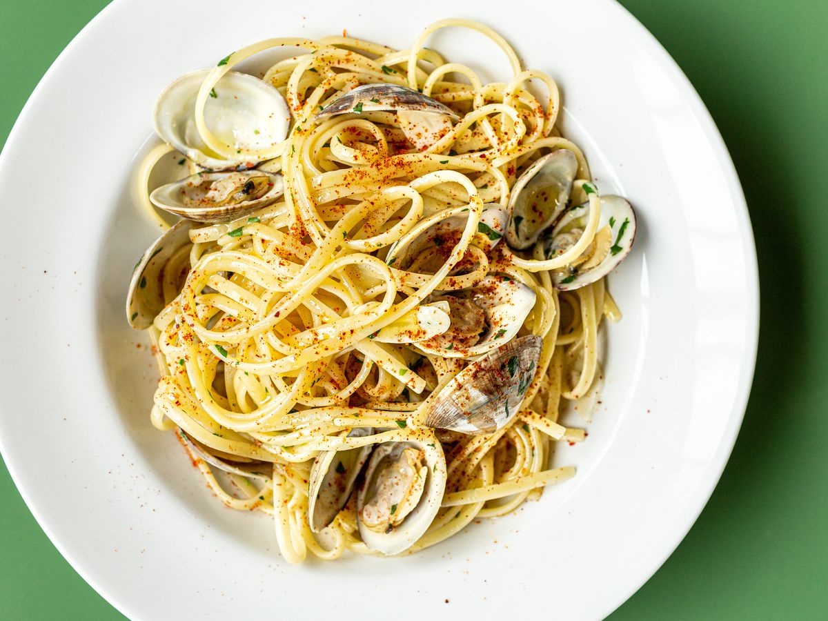 A bowl of linguine, mussels, and clams that’s sprinkled with chile.