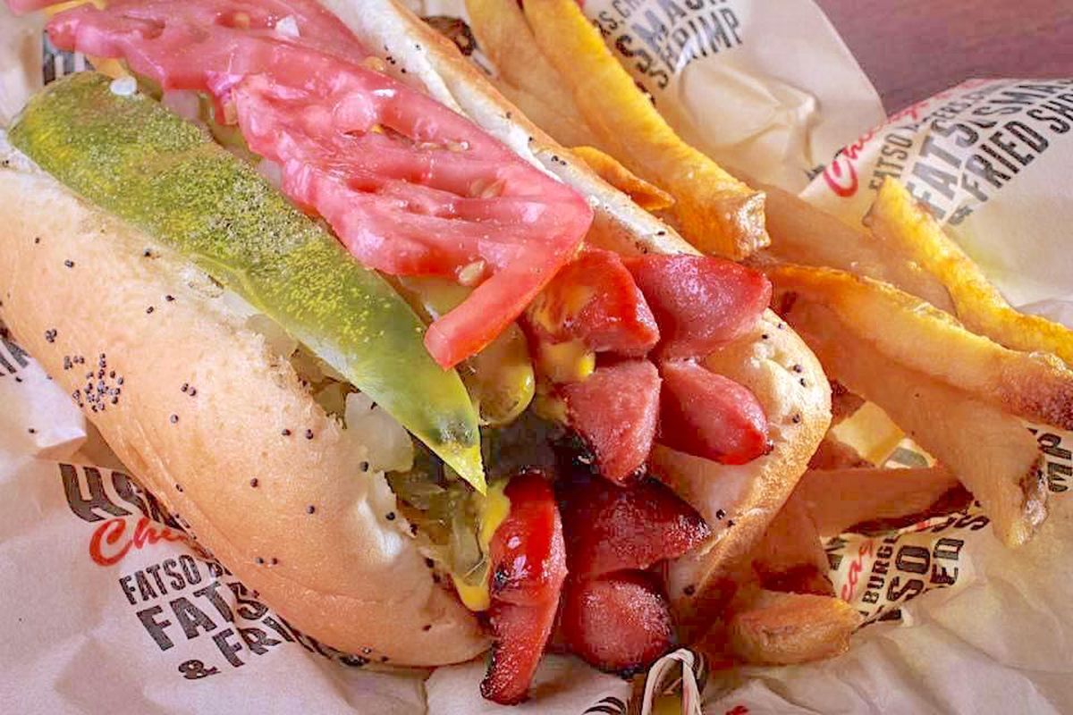 A Chicago-style char dog on a bun with french fries.