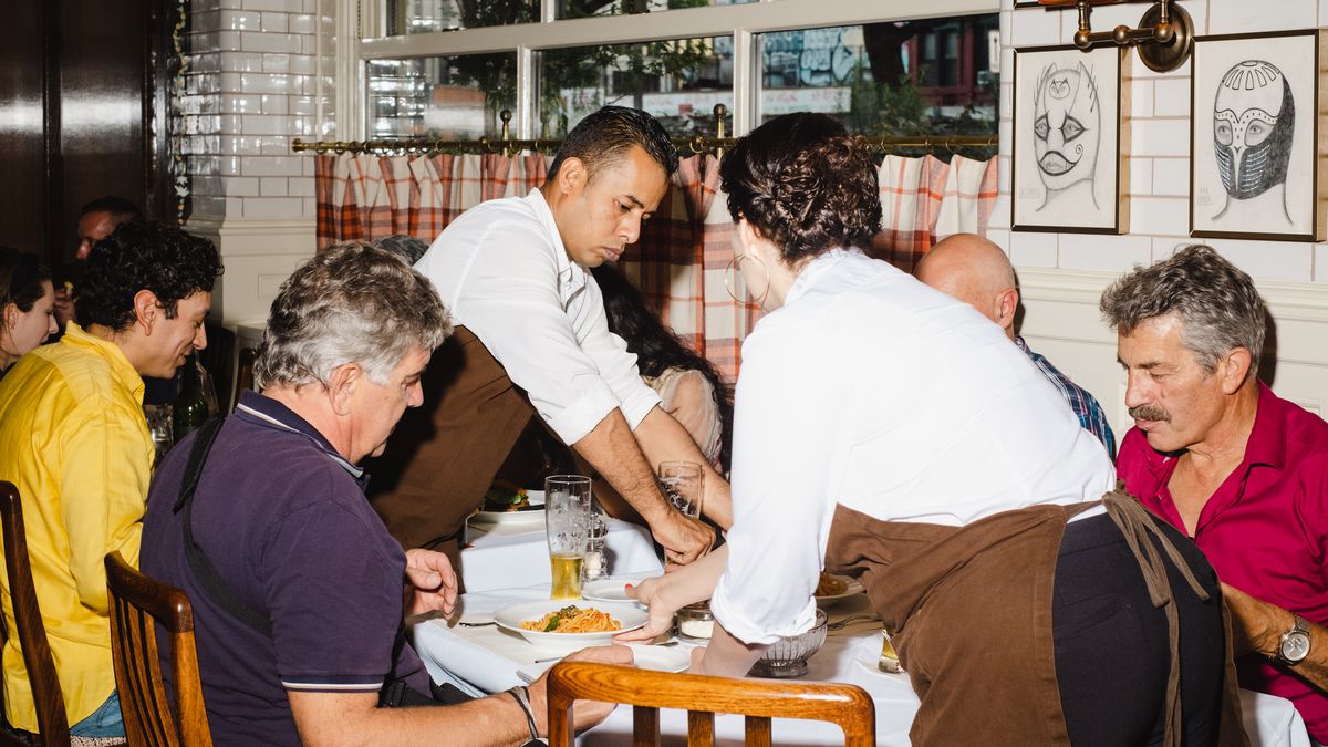 Staffers in white shirts and brown aprons serve spaghetti pomodoro to a table at Corner Bar.