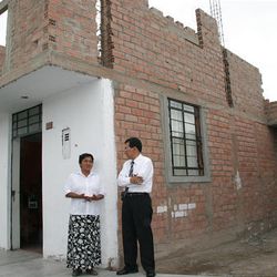 Rosa Maurtua, whose home was destroyed in 2007 quake, and LDS engineer Rolando Castilla stand by her new home in Pisco, Peru, that was part of LDS Church rebuilding project.