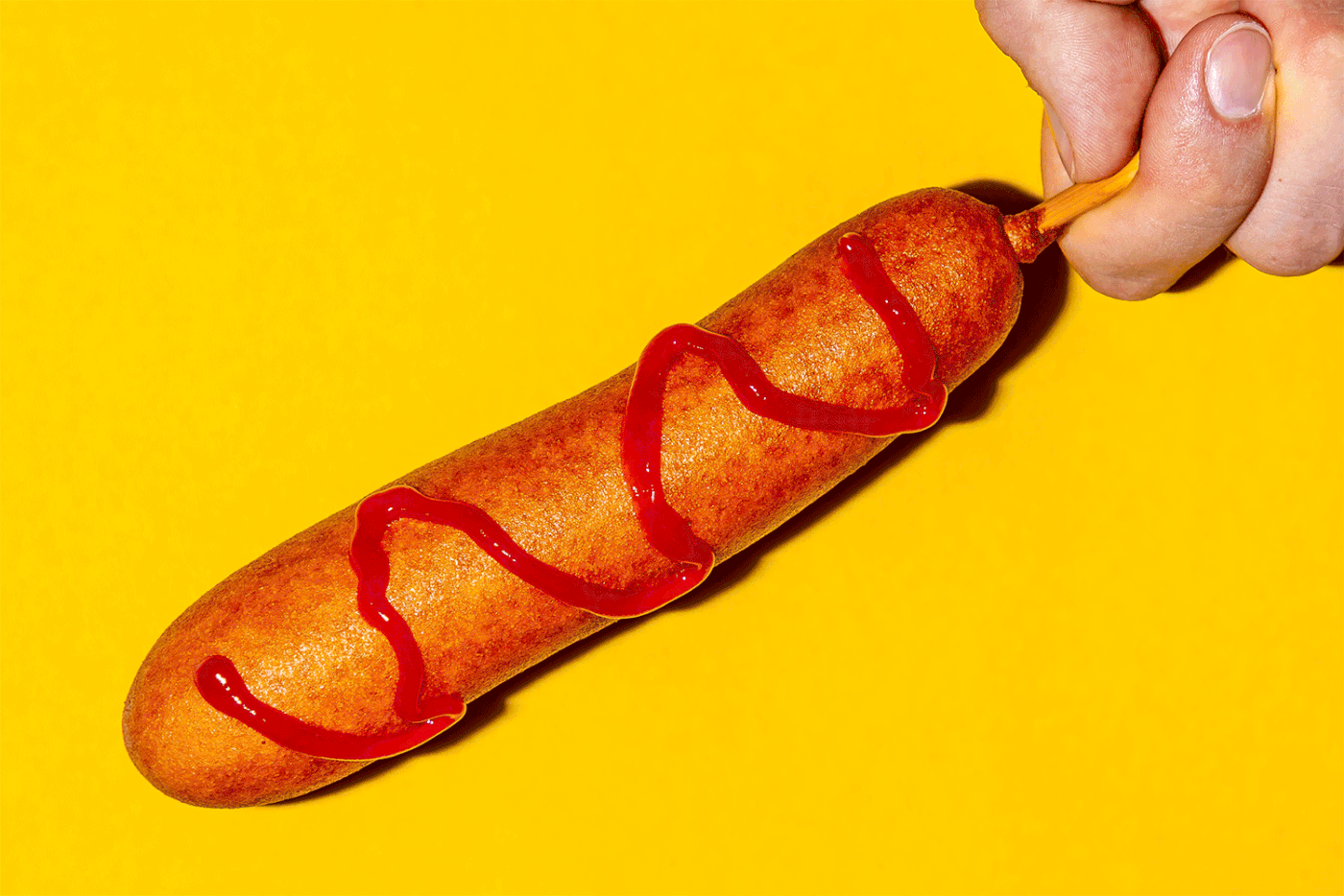A corn dog against yellow background