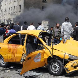 This photo released by the Syrian official news agency SANA, shows Syrians inspecting a damaged car at the scene of a car bomb attack near the Sabaa Bahrat Square, one of the capital's biggest roundabouts, in Damascus, Syria, Monday, April. 8, 2013. A car bomb rocked a busy residential and commercial district in central Damascus on Monday, killing more than a dozen with many more injured and sending a huge cloud of black smoke billowing over the capital?s skyline, Syrian state-run media said. (AP Photo/SANA)