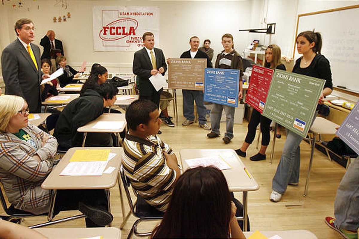 Scott Anderson, rear, and other financial professionals discuss the costs of credit with West High students Thursday.