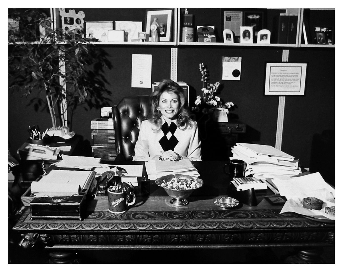Smiling woman sits behind a large desk.