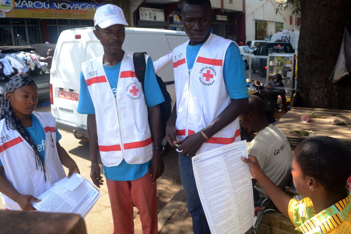 Members of the Guinean Red Cross speak with a resident during an awareness campaign on the Ebola virus