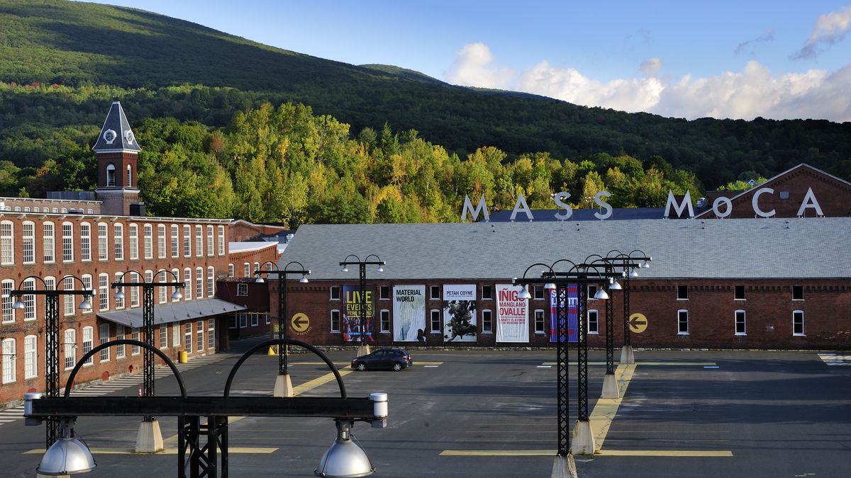 Exterior view of Mass Moca, a sprawling brick museum, with green mountains in the background