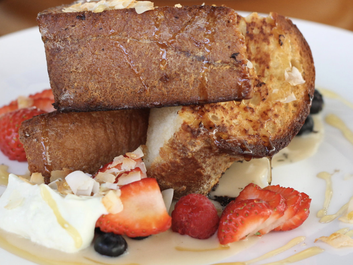 A closeup of French toast with berries and cream.