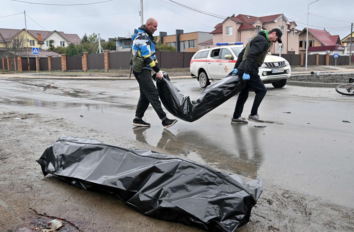 کارگران در شهر بوچا، نه چندان دور از پایتخت اوکراین، کیف، در 3 آوریل 2022، کیسه های جسد حمل می کنند.
