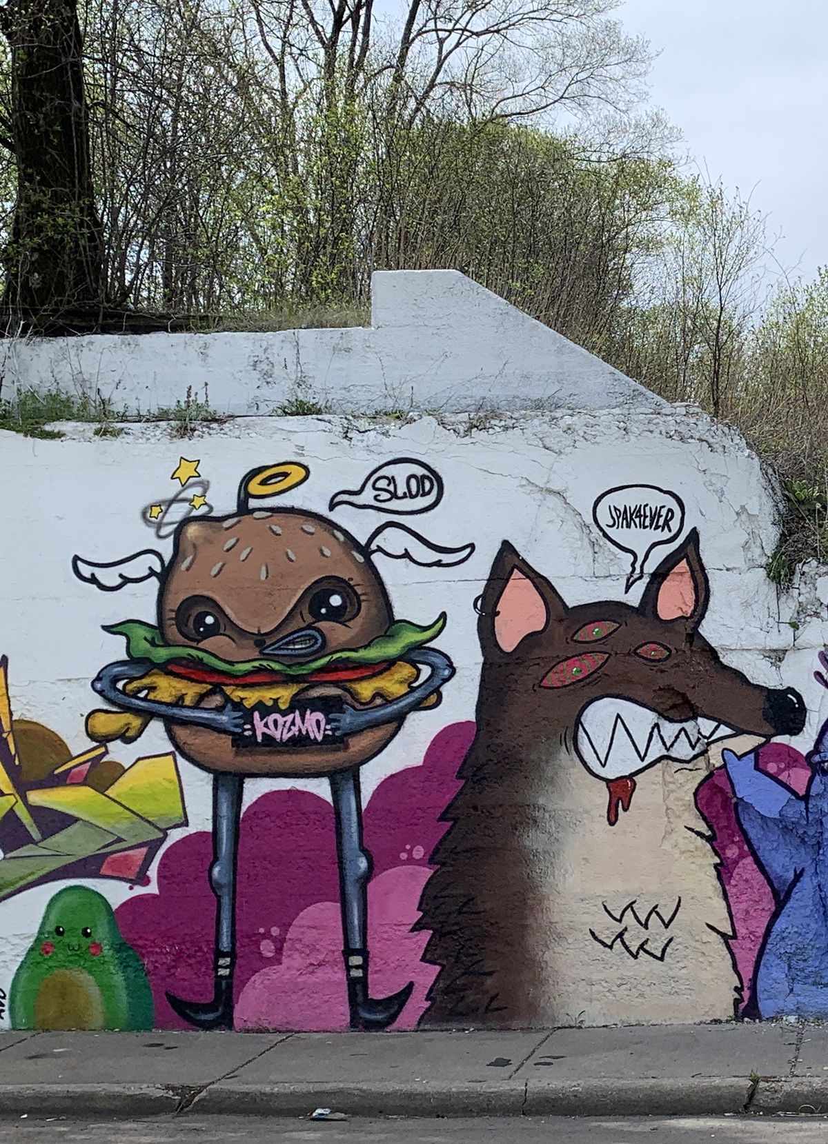 KOZMO’s burger character with arms and legs stands next to the “fox demon” of Avondale artist Jeff Pak — who goes by JPAK4EVER. The “fox demon” was inspired by a manga that Pak read called “Chainsaw Man.”