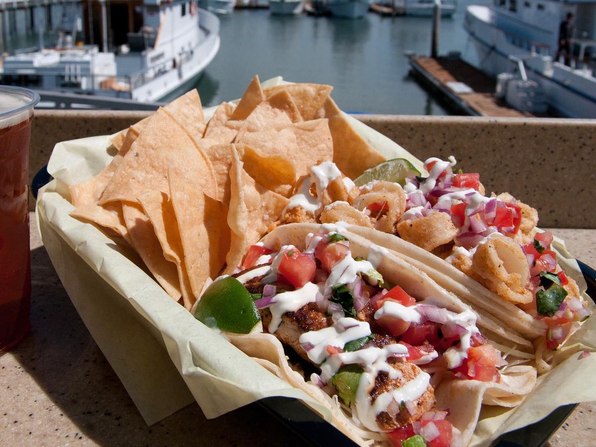 Two fried fish tacos with chips.