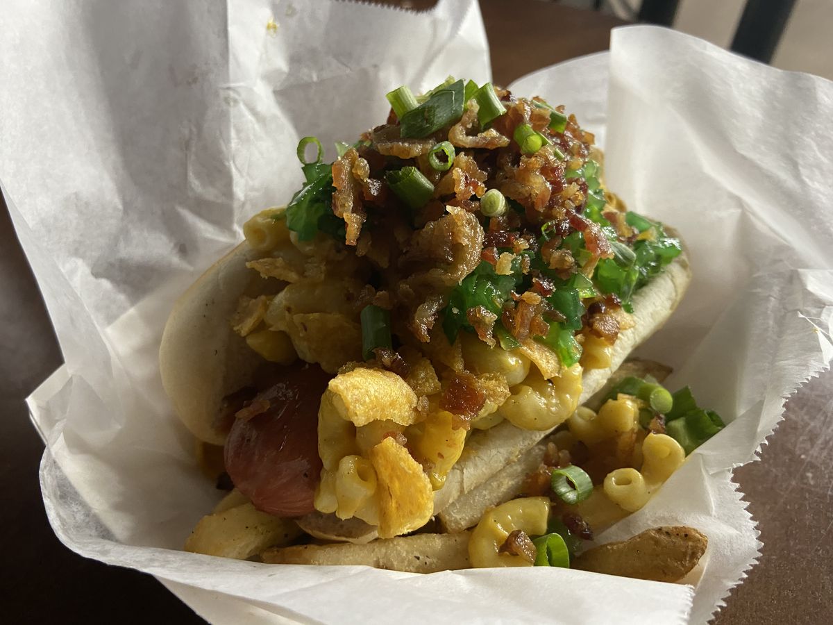 Hotdog with a lot of mac and cheese, bacon, and relish.