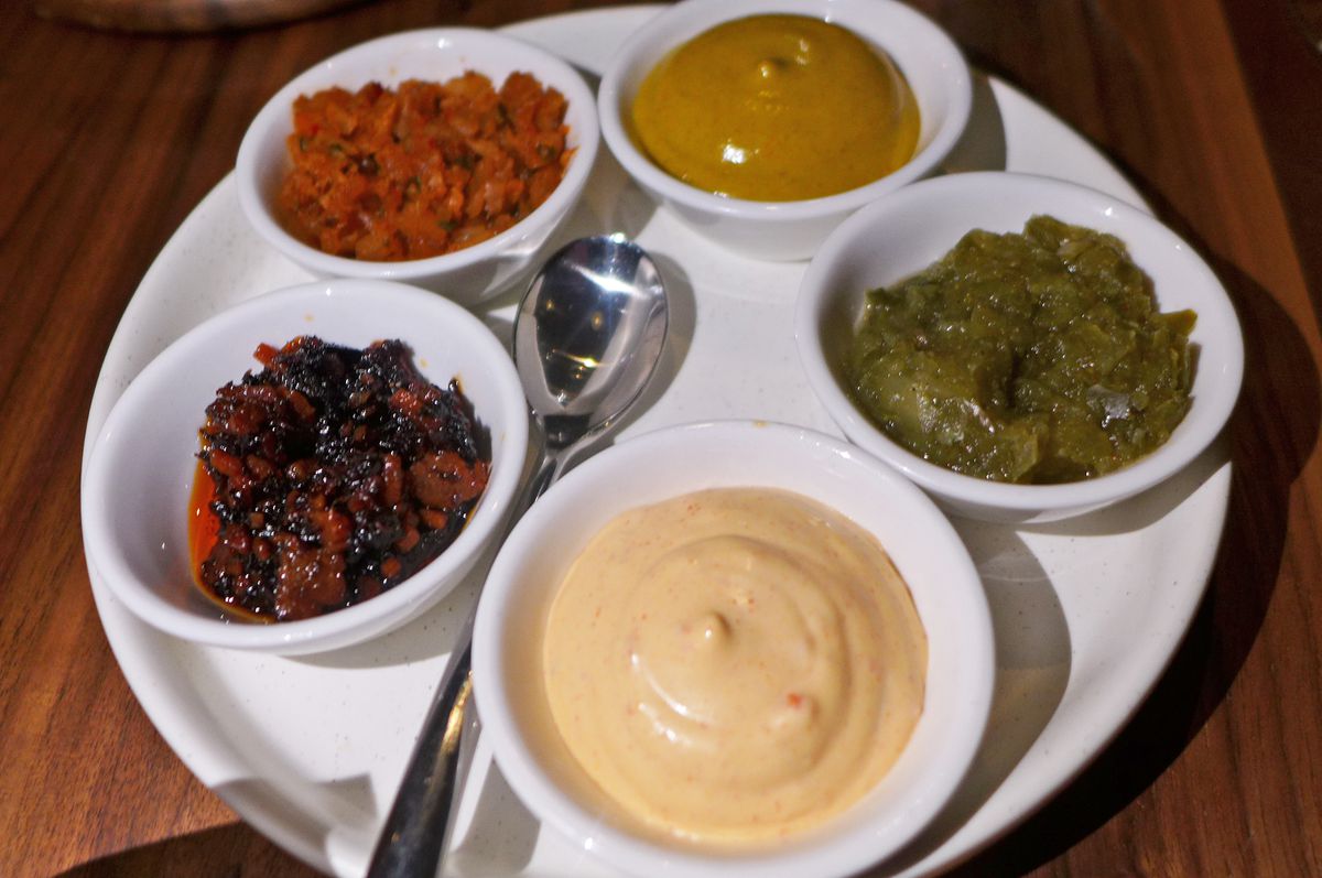 Five shallow dishes of various hues on a white plate.