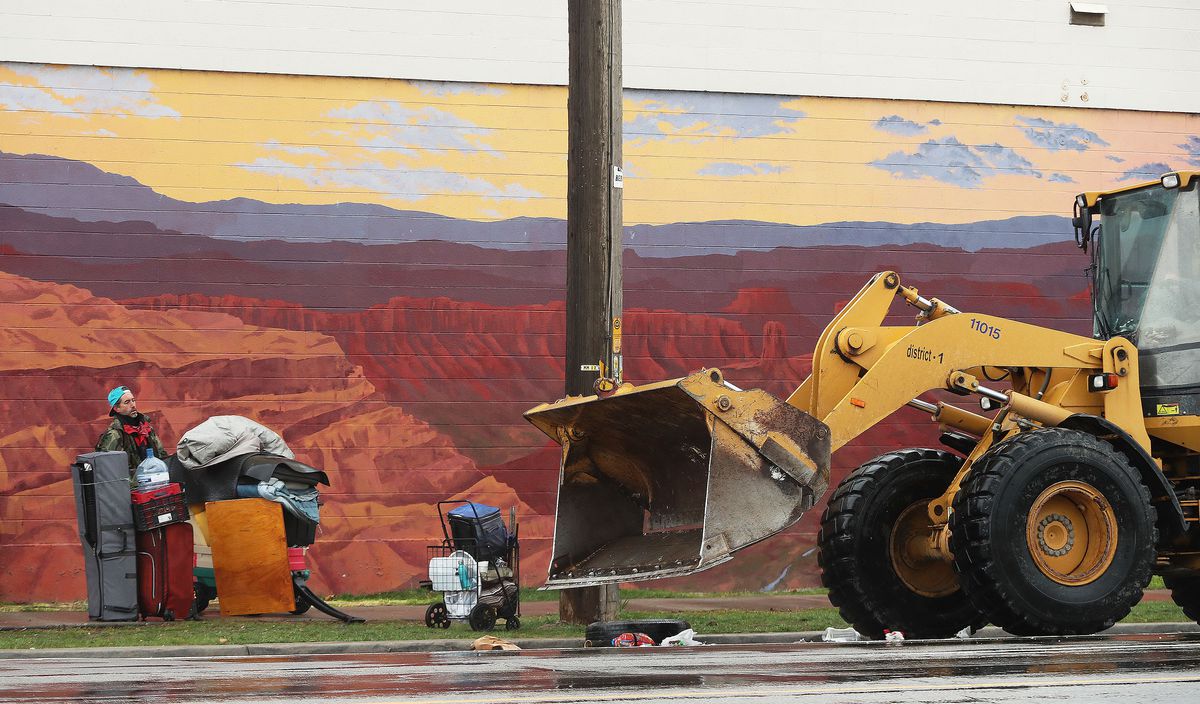 A homeless man stacks his possessions as a bulldozer clears other items left in a homeless camp in Salt Lake City on Wednesday, April 14, 2021.