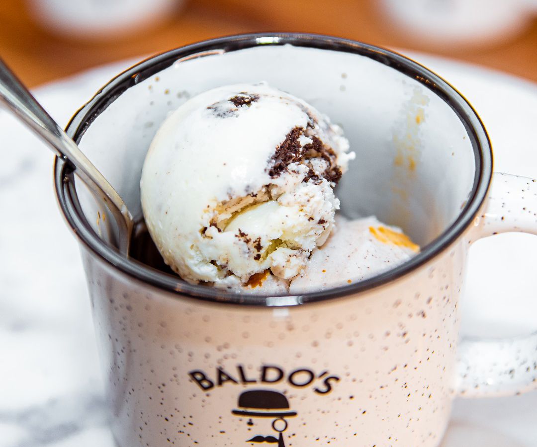 A coffee mug with the Baldo’s logo reveals several scoops of ice cream and a spoon.