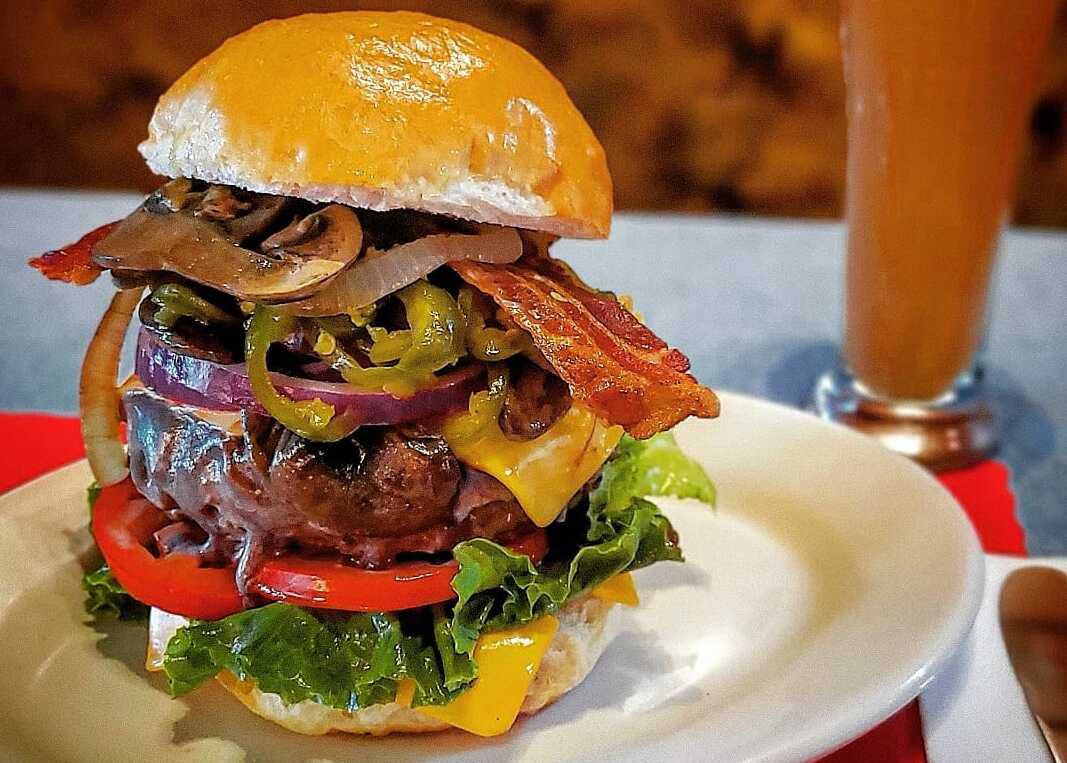 A burger topped with grilled onions and mushrooms, cheese, bacon, and more. 
